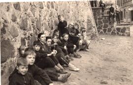 Kinder sitzen an einer Mauer