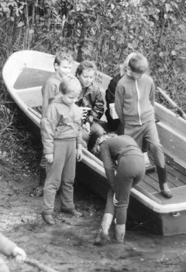 Erzieherin und Kinder in einem auf Ufer gezogenen Kahn