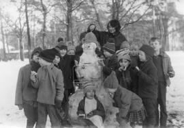 Kindergruppe mit Erzieherin vor Schneemann