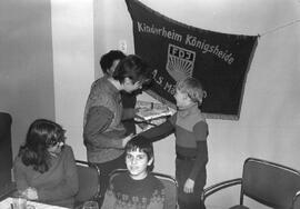 Übergabe Geschenk an einen Jungen  vor Fahne Kinderheim