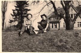 Zwei Frauen sitzen vor Gebäude