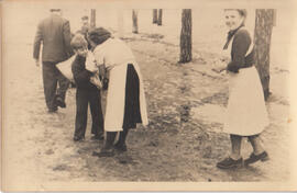 Junge mit Wäschesack Frauen in weißer Schürze